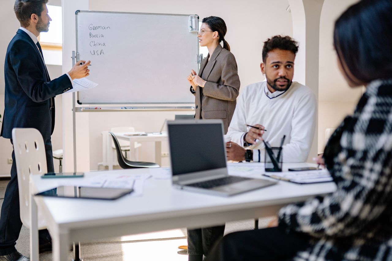 The Art of Drawing Readers In: Your attractive post title goes here A diverse group of professionals engaged in a collaborative office meeting with laptops and a whiteboard.
